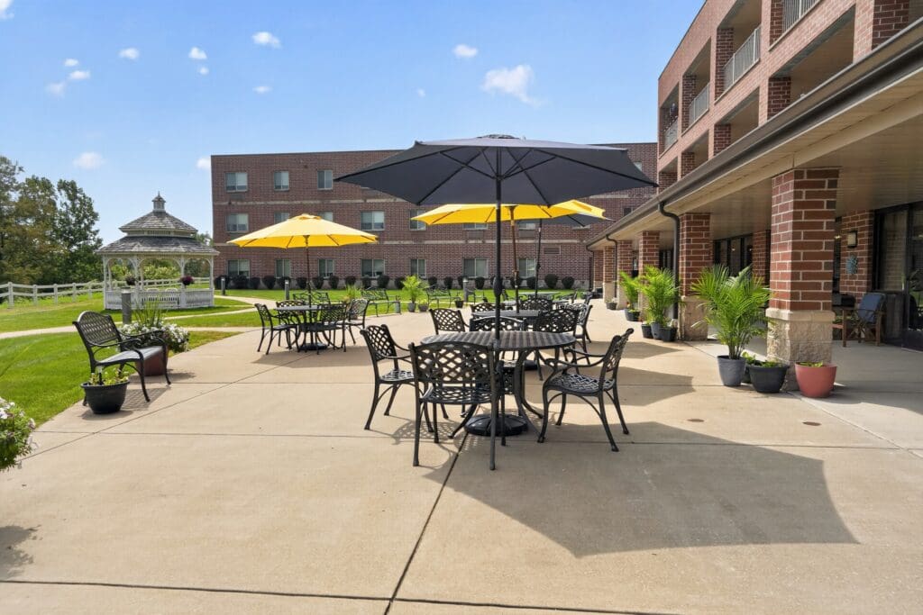 Inviting outdoor patio with black and yellow umbrellas, surrounded by lush greenery and a charming gazebo.