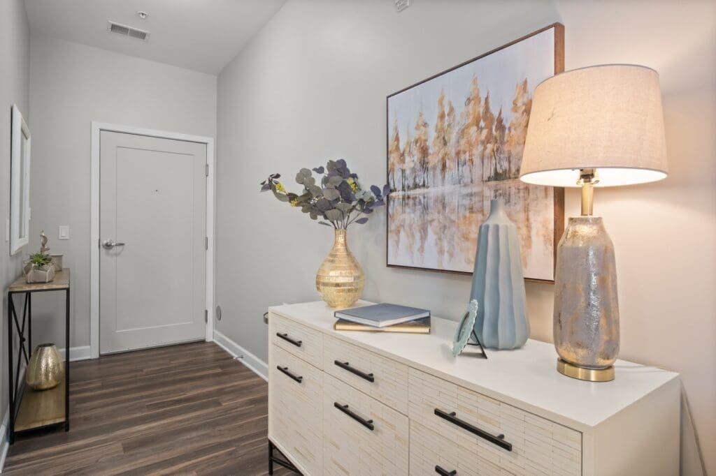 Photo-4-Large - Grace Management Welcoming hallway adorned with elegant decor, featuring a console table, modern artwork, and a stylish lamp, enhancing the ambiance.