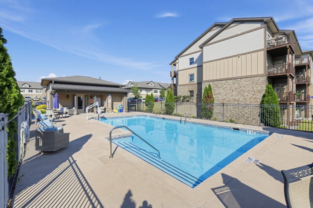 Refreshing outdoor pool surrounded by upscale seating and vibrant landscaping at a luxury senior living community.