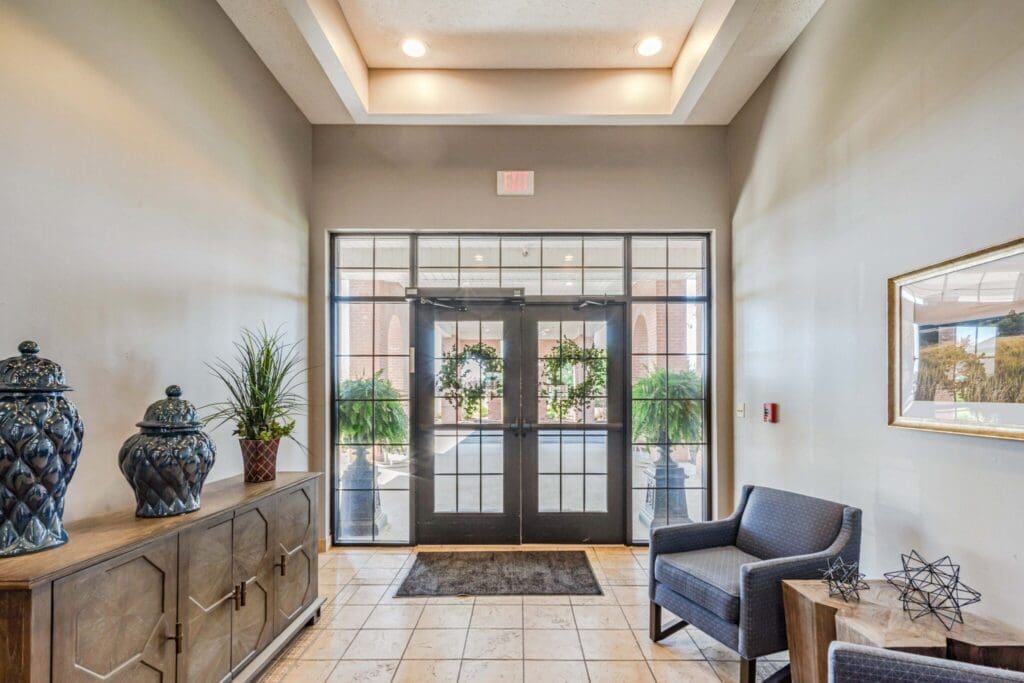 Inviting lobby with elegant decor, potted plants, and natural light streaming through glass doors, creating a welcoming atmosphere.