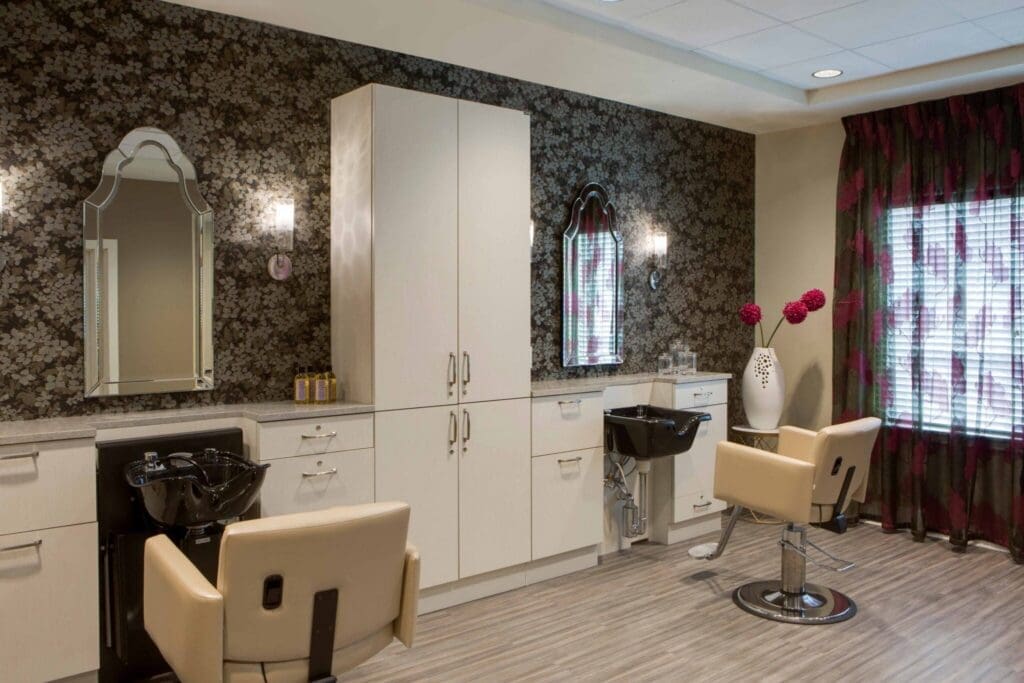 Elegant salon interior featuring stylish chairs, floral wallpaper, and a bright window, creating a welcoming atmosphere.