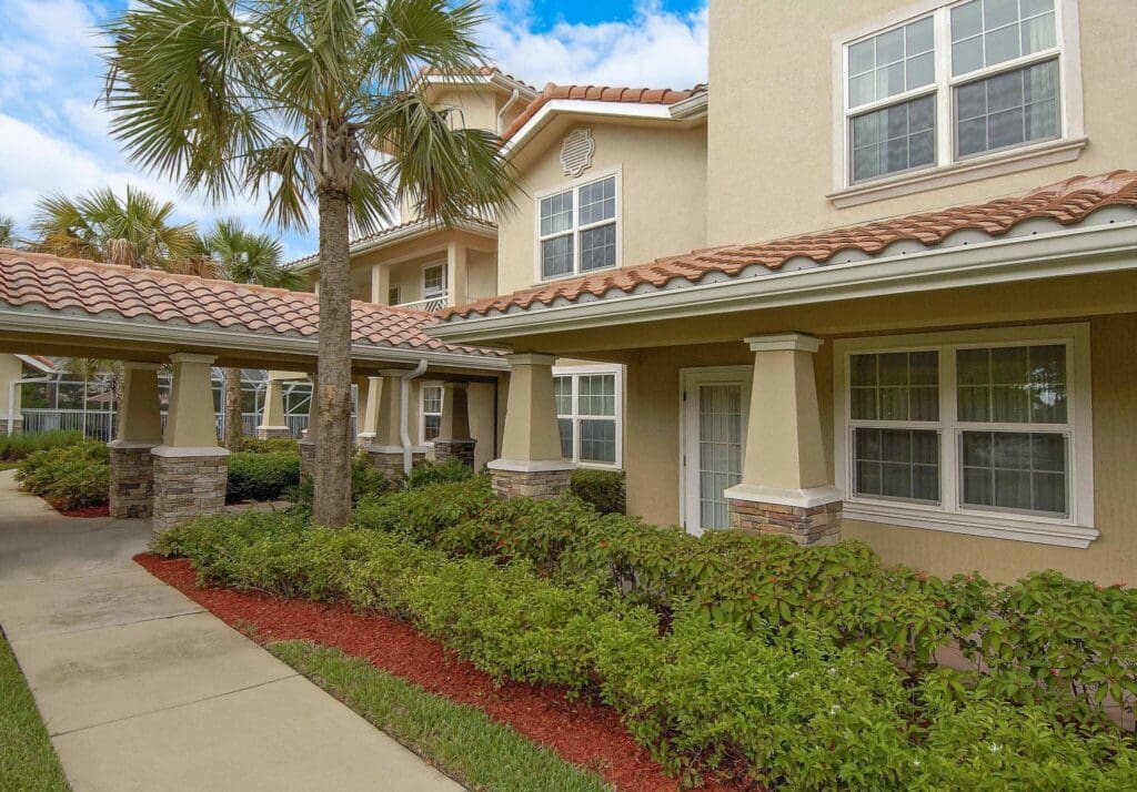 Lush landscaping and elegant architecture adorn the entrance of a senior living community, inviting a vibrant lifestyle.