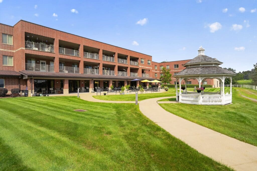 Elegant senior living community featuring lush green lawns, a charming gazebo, and welcoming outdoor seating areas.