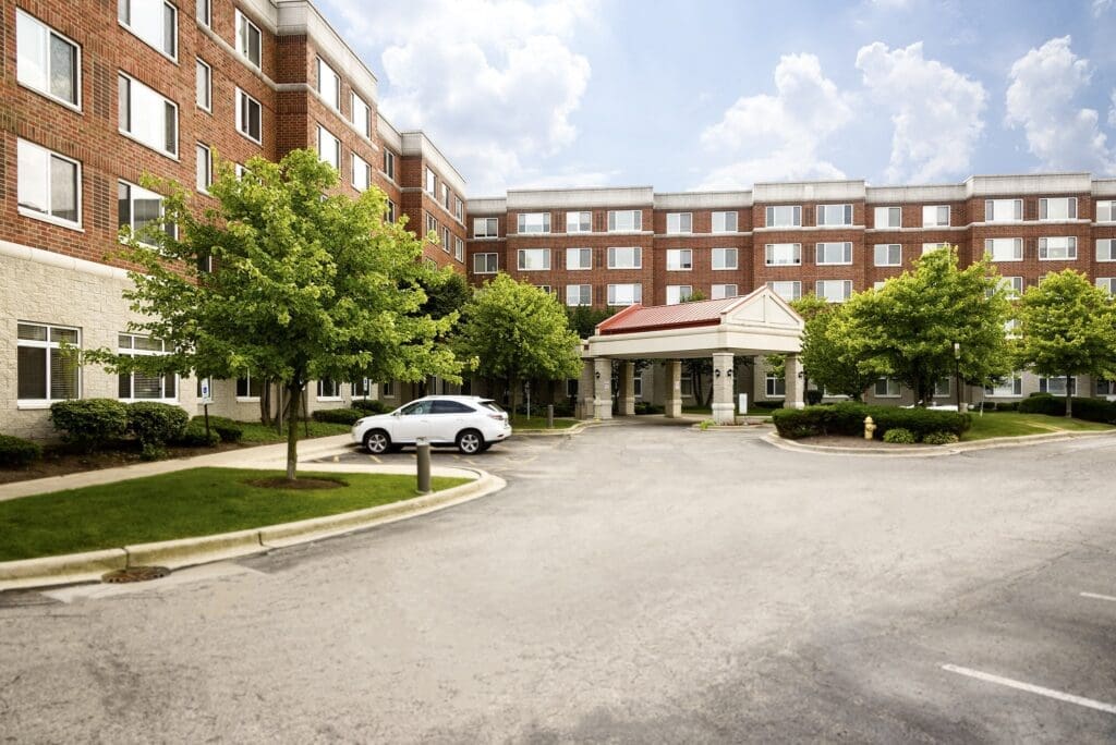 Elegant senior living community surrounded by greenery, featuring a welcoming entrance and modern architecture.