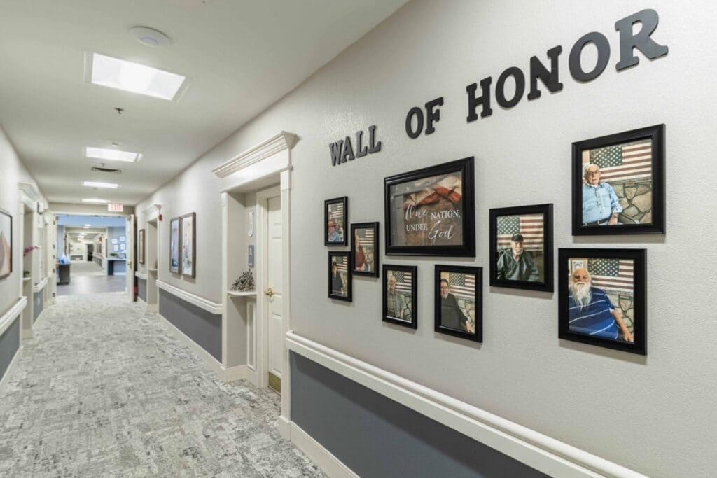 Hallway featuring a Wall of Honor with framed portraits of veterans, celebrating service and sacrifice in a warm environment.