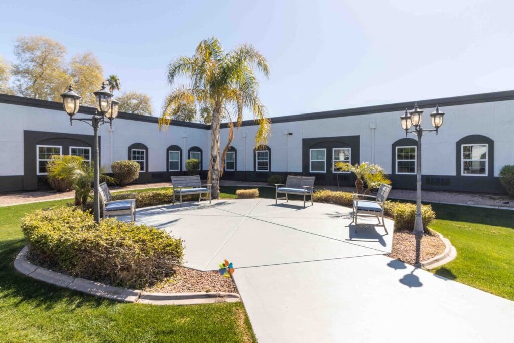 Bright courtyard featuring palm trees, benches, and lush landscaping, inviting seniors to enjoy an upscale outdoor experience.
