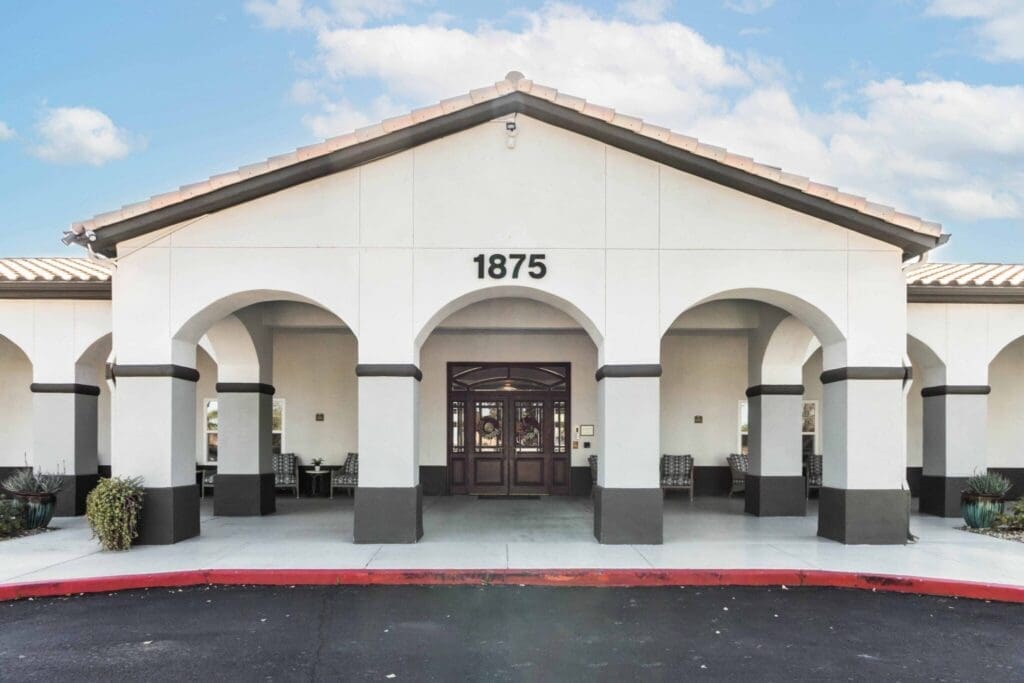 Welcoming entrance of an upscale senior living community, featuring arched architecture and elegant seating areas.