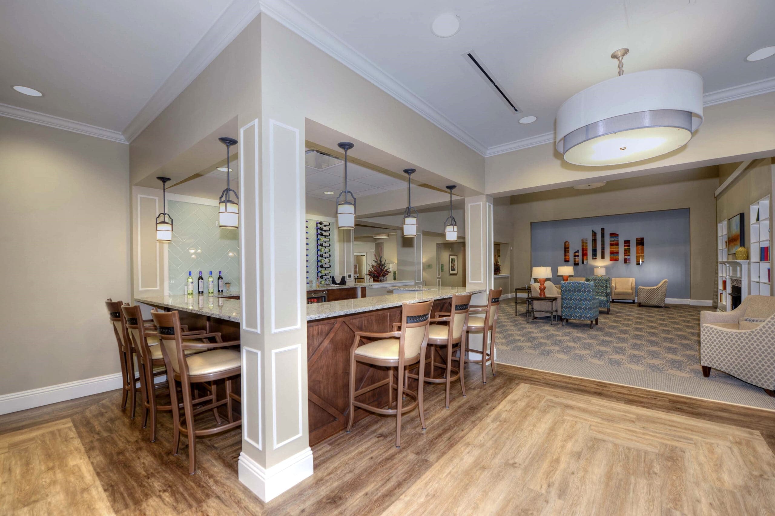 - Grace Management A bar area with bar stools and sitting sofa chairs in the background at Beach House, a senior living community.