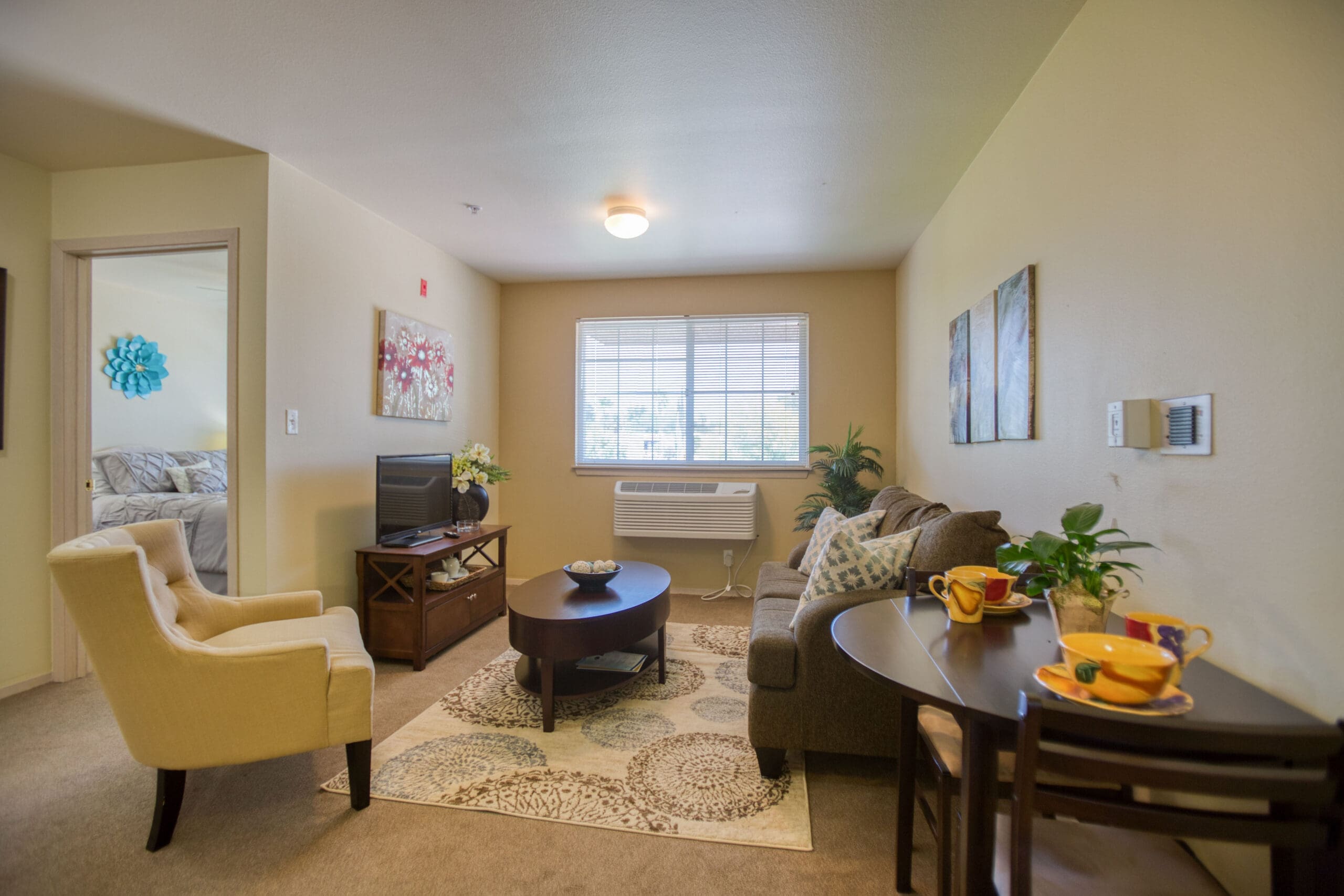 Interior image of a Vista Pointe at Green Valley apartment with a living room, dining area, and peek into the bedroom.