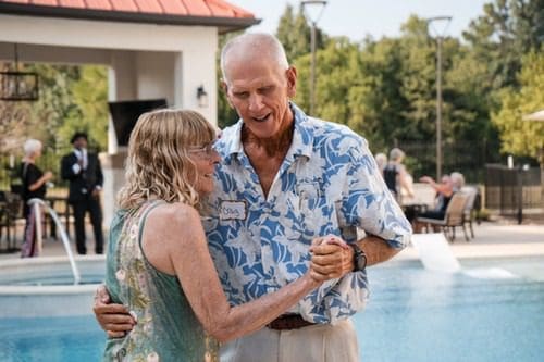 A man and woman dance together by the pool during a social event at The Lakes at Woodhaven Village, a retirement community near Huntsville, TX.