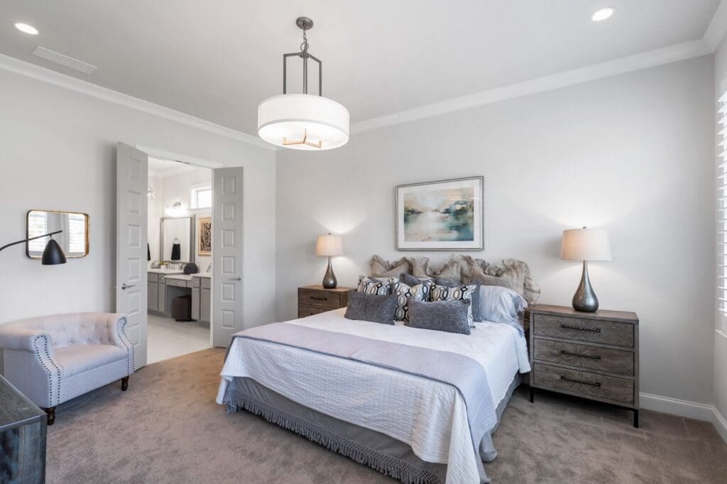 - Grace Management A photo of the large Master Bedroom showing the bed with bedside tables and lamps on each side at Celebration Village Forsyth, a senior living community near John's Creek, GA.