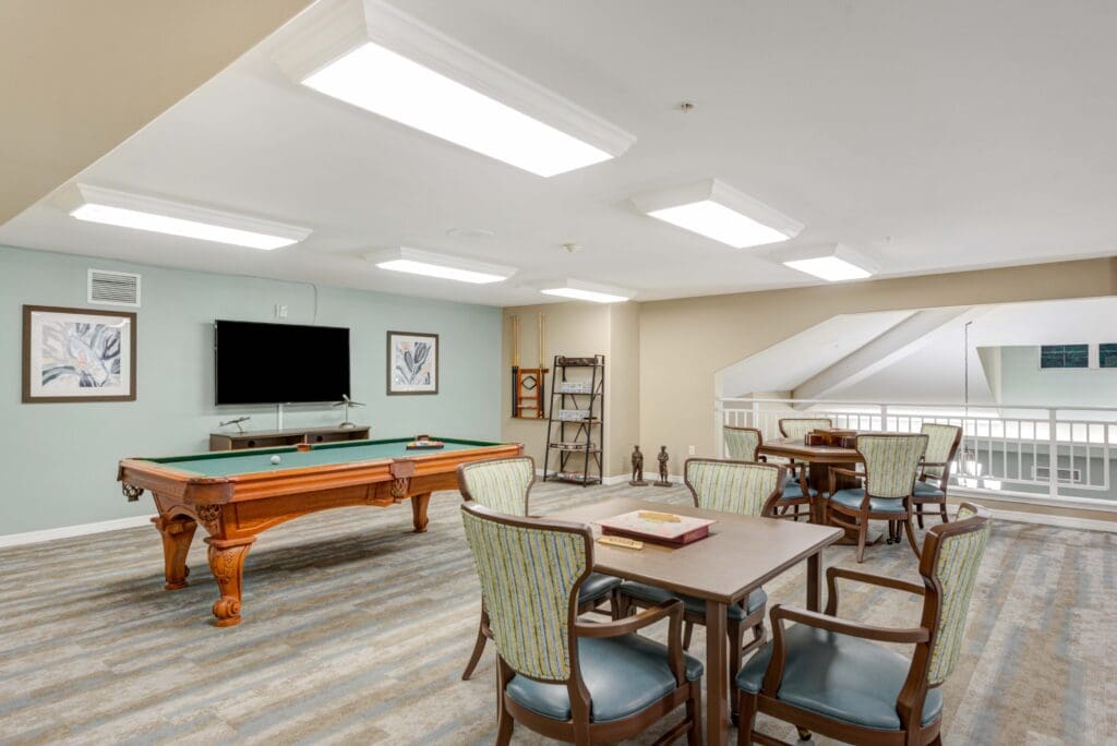 - Grace Management Bright activity room with pool table and gaming tables at Windward Palms, a premier senior living community near Boca Raton.