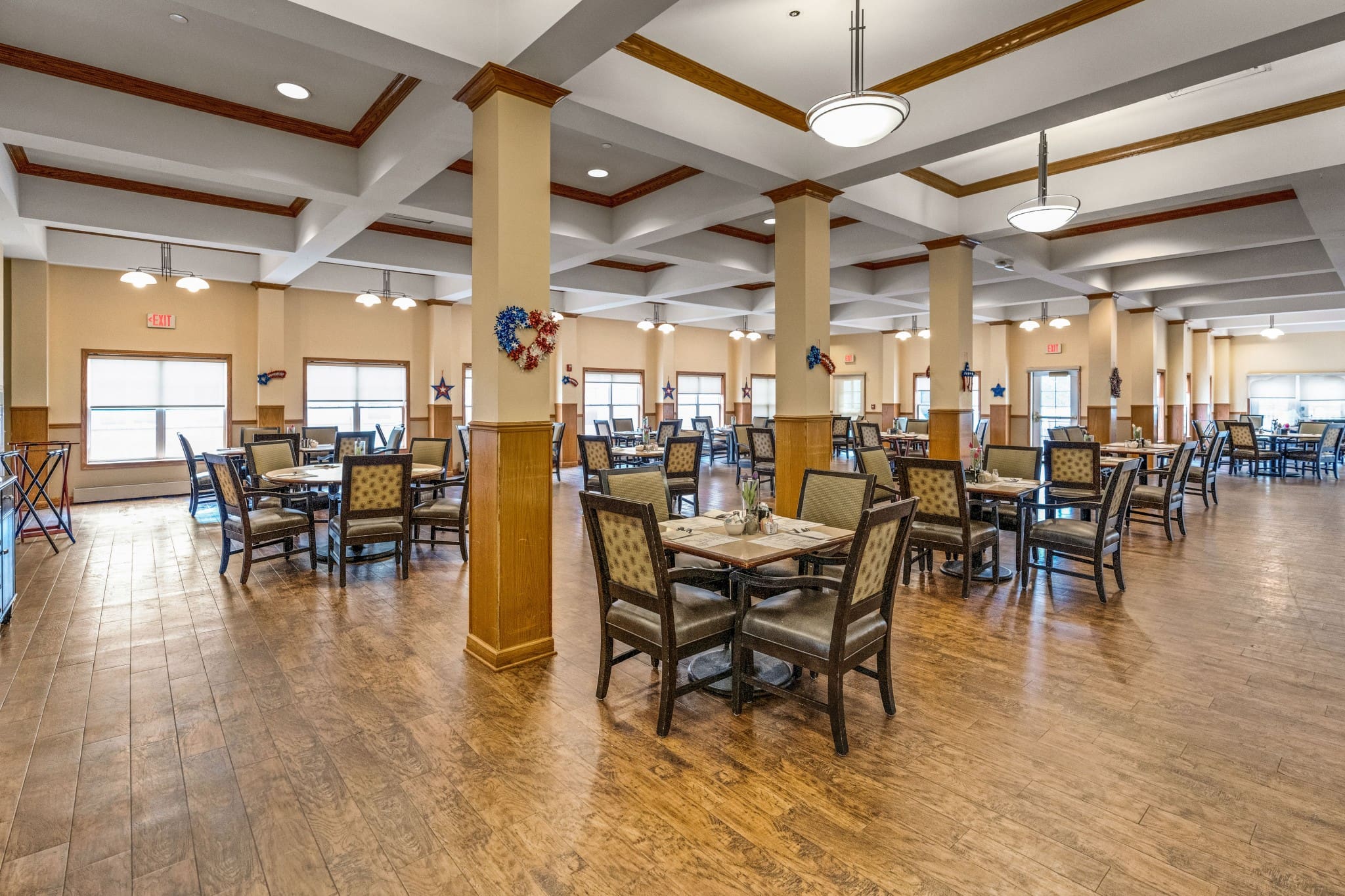 - Grace Management A dining room with square made-up tables and chairs at Town Village Sterling Heights, a senior living community near Detroit.