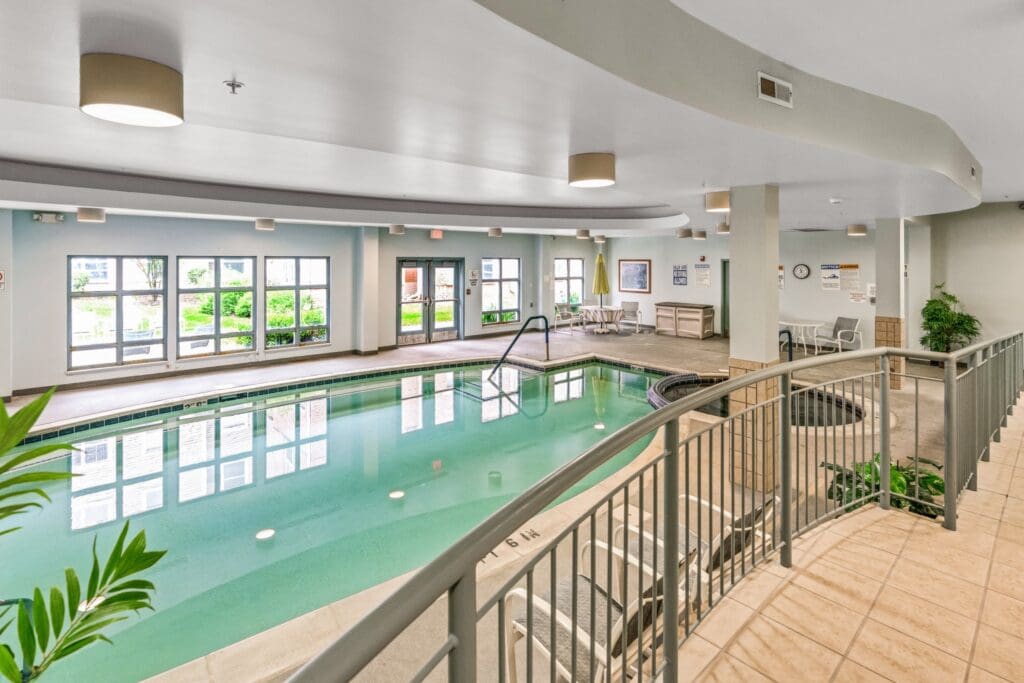 - Grace Management An indoor pool with poolside tables and chairs at Town Village Sterling Heights, a senior living community near Clinton Township, MI.