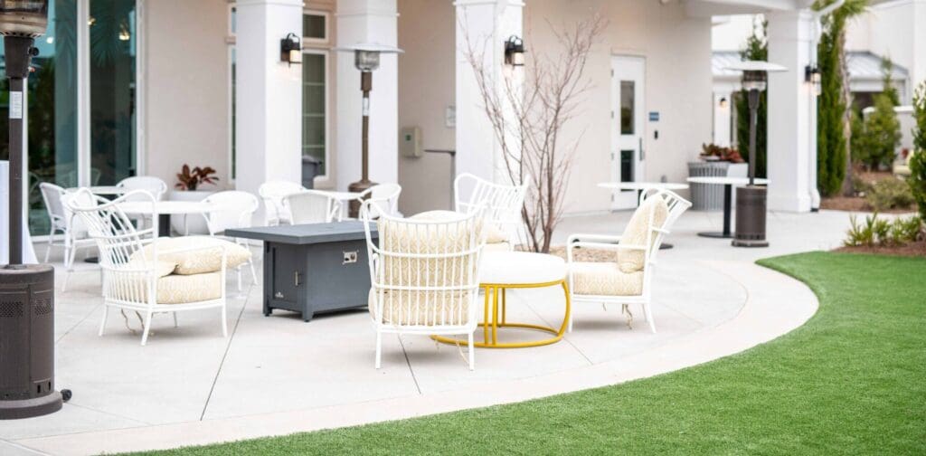 Portside at Grande Dunes cafe lawn with white cushioned chairs and a white cushioned coffee table.