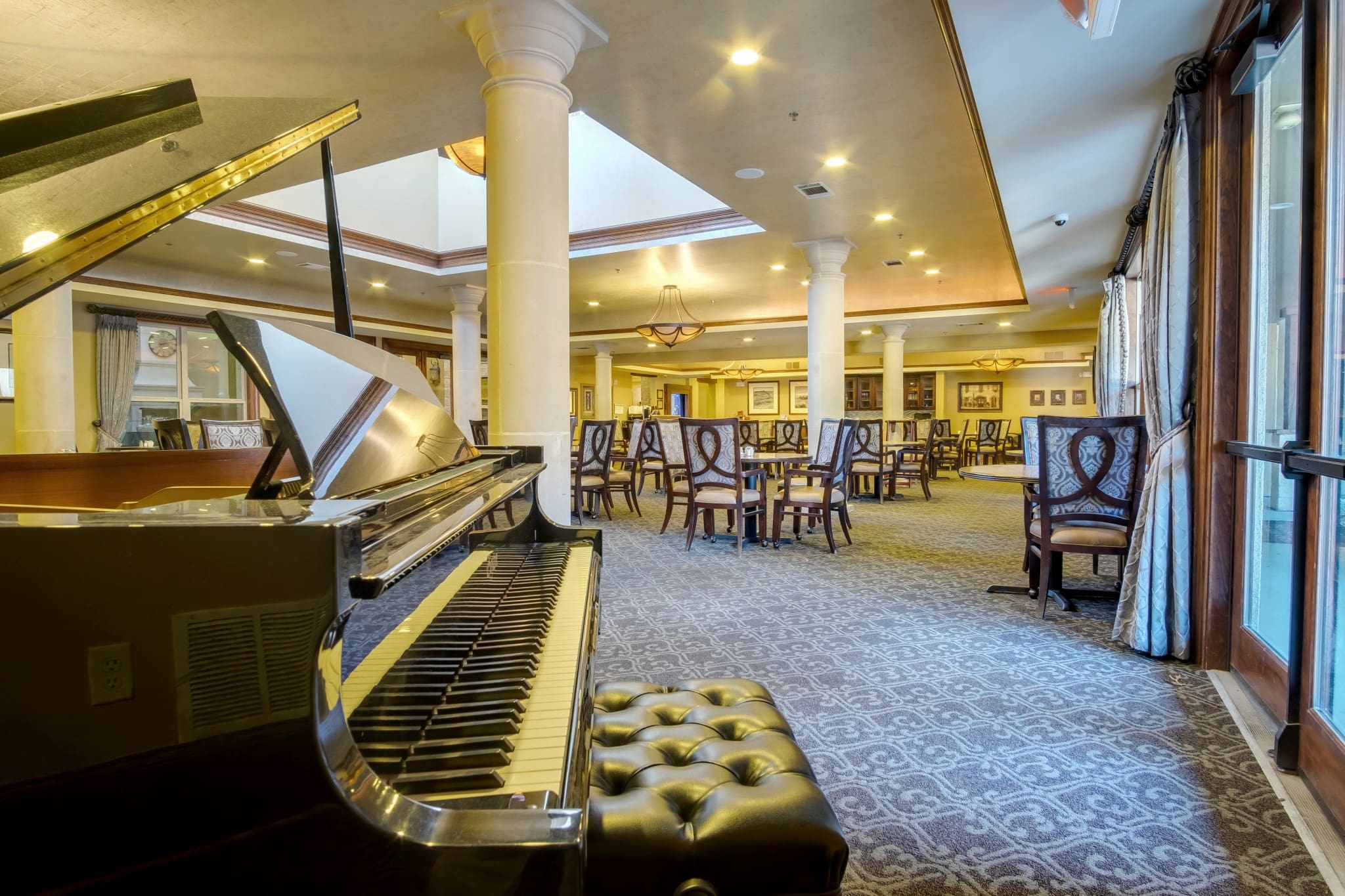 Interior image of the dining hall, including the grand piano for music at The Landon at Lake Highlands, a Forest Hills senior living option.