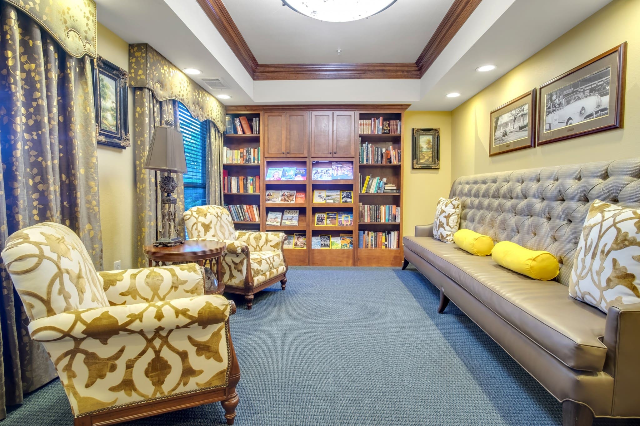 Interior image of the common area with comfortable chairs and tables. There is a fireplace to sit by, books to read, and games to play at Lake Highlands, an independent living community near Rockwall, TX.