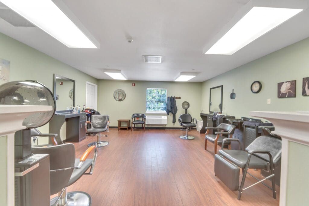 A full-service salon with professional styling chairs, wash stations, and a hair dryer at Collier Park, offering senior living near Lake Charles, LA.