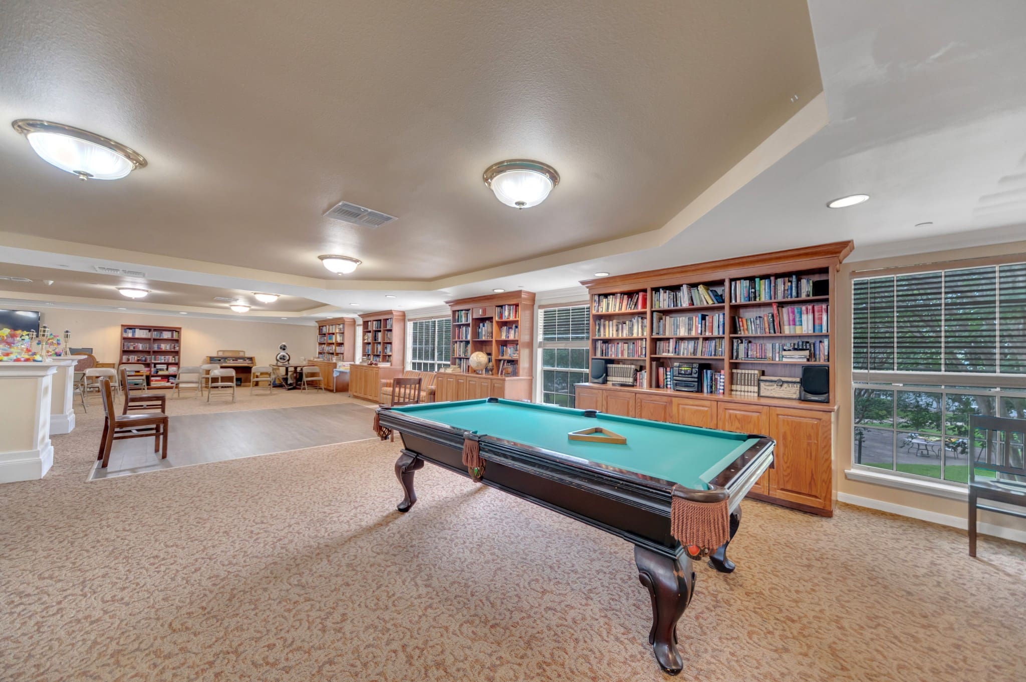 Interior shot of Collier Park's recreation room with lots of bookcases, a pool table, a dance floor, and more.