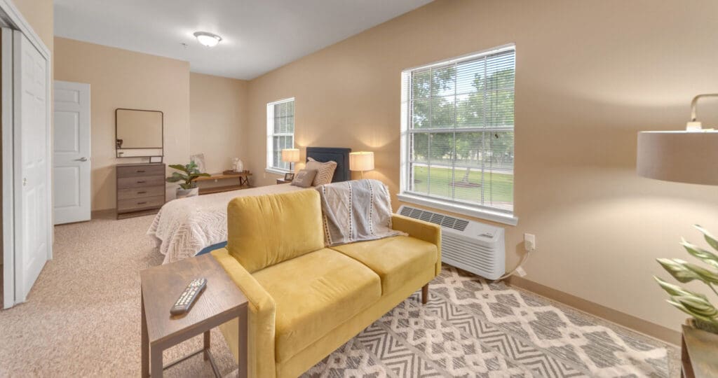Interior shot of Collier Park, showing a studio apartment with a combined, spacious living room and bedroom. The windows let in lots of natural light.