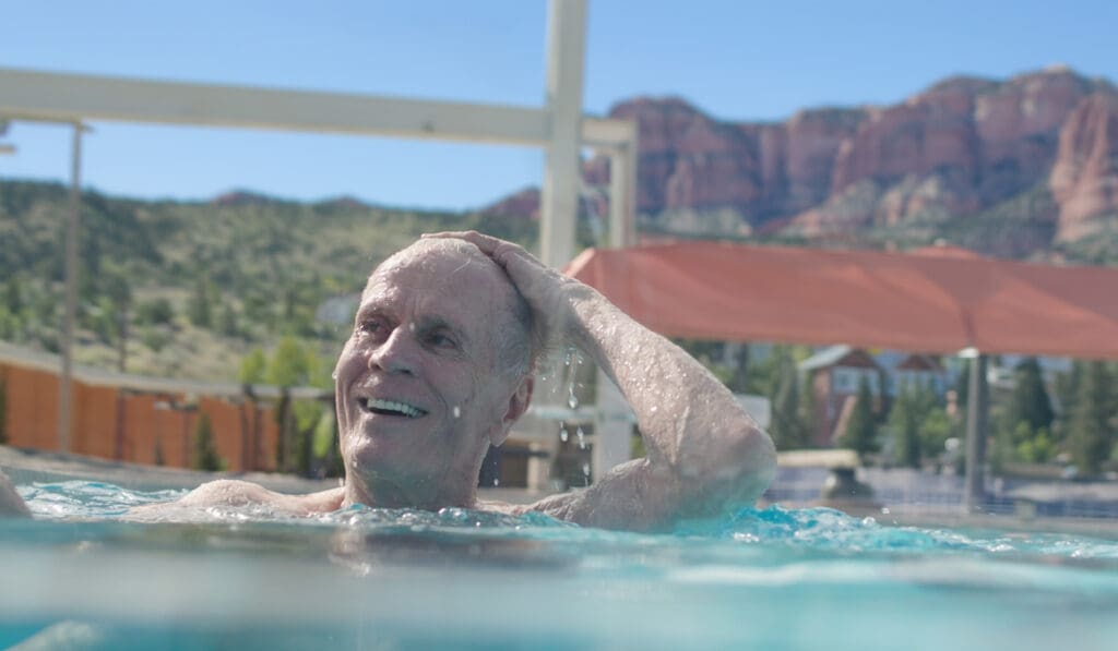 - Grace Management Older man enjoying a swim with scenic red rock views at Snow Canyon Retirement Community, offering vibrant senior living near St. George, Utah.