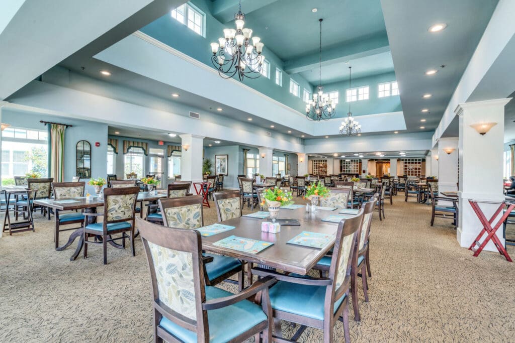 Interior image of a spacious and welcoming dining hall. There is lots of natural light, calm colors, and plenty of seating for socializing over meals at Camellia at Deerwood, senior living community near Ponte Vedra.