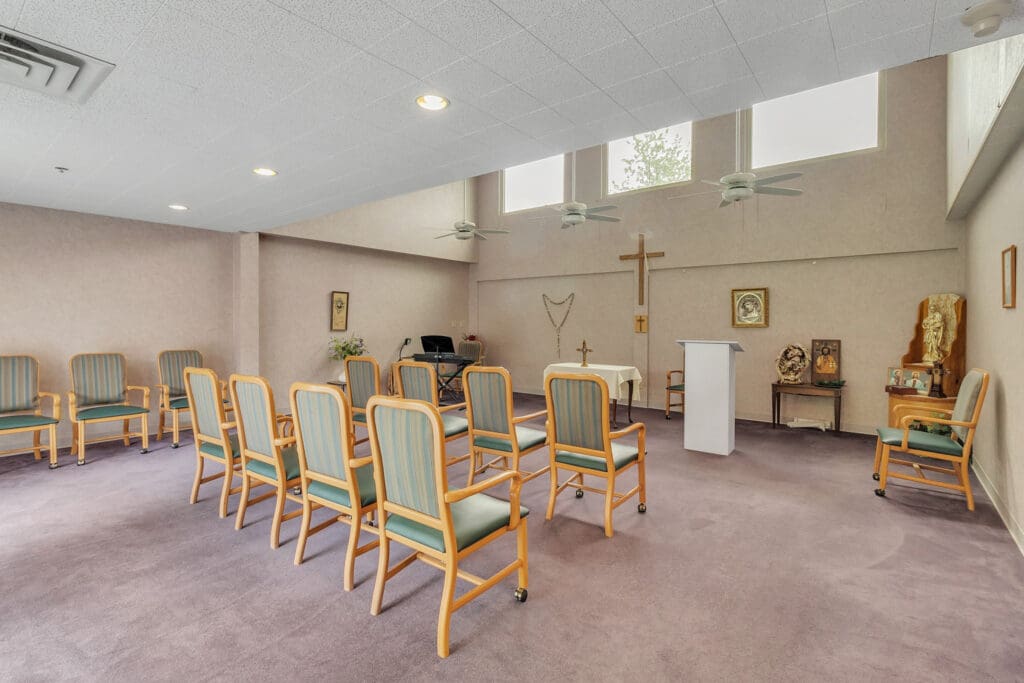 - Grace Management A chapel room with green and orange chairs facing a white podium with a golden cross on the wall at Northgate Park.