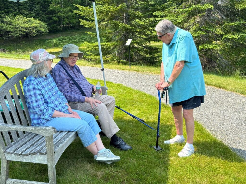 Residents sitting on a bench outside are talking to each other at Dirigo Pines, a senior living community near Brewer, Maine.