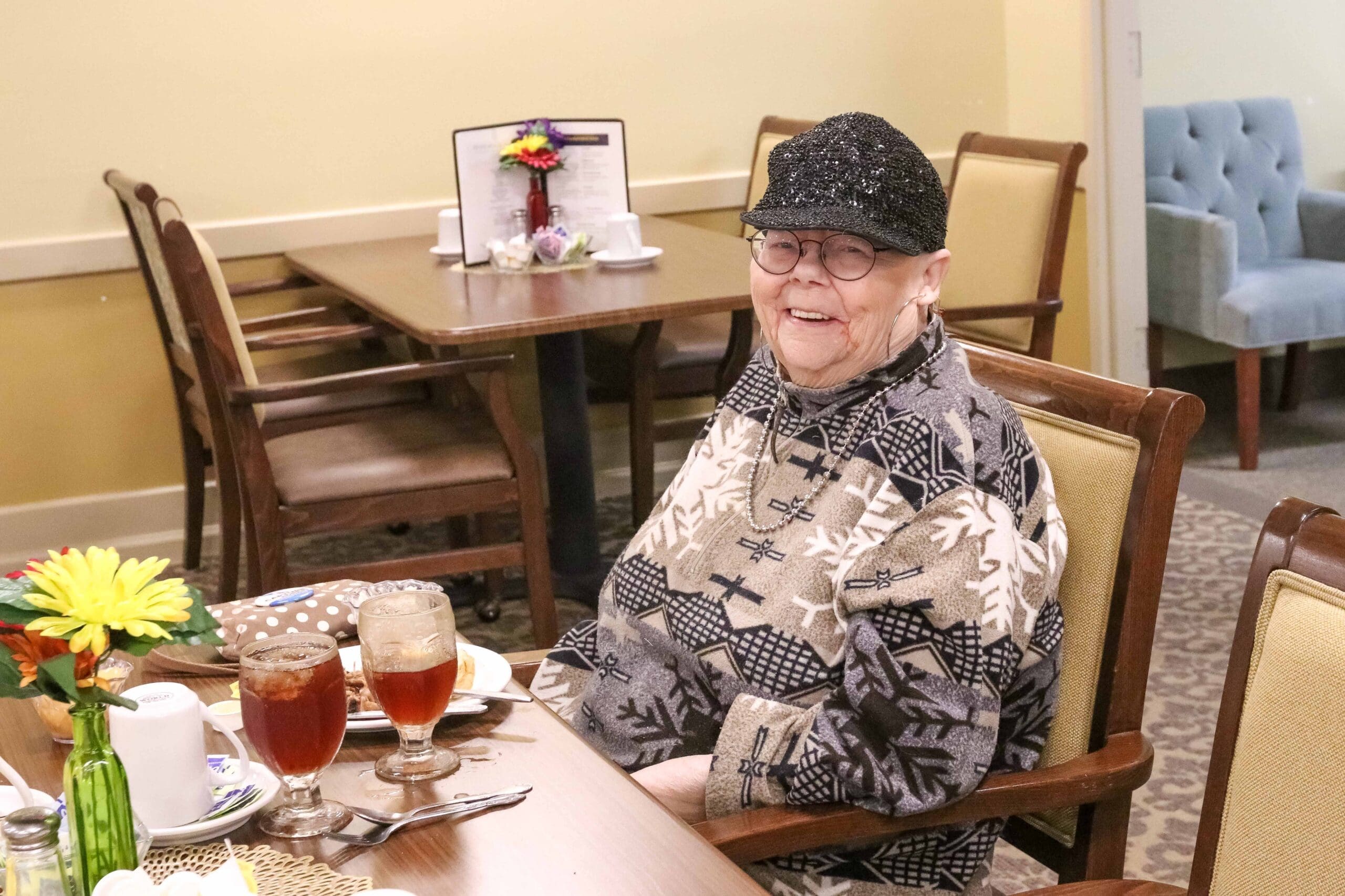- Grace Management Smiling resident enjoying a meal at Sedgwick Plaza, a quality senior living community.
