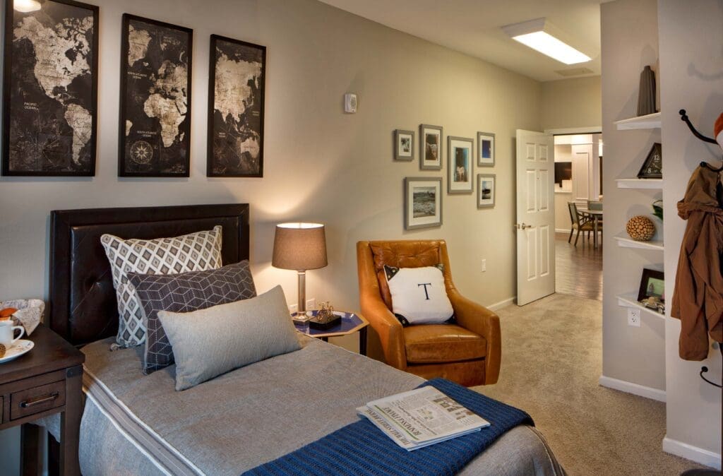 Jim-Wilson3D3A5879RT1A-1-1024x674 - Grace Management Cozy, elegantly designed room featuring a bed, comfortable chair, decorative artwork, and vibrant natural light.