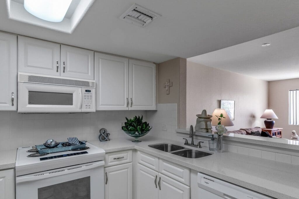 - Grace Management A kitchen with white cabinets, microwave, oven, sink, and white countertops at The Ranch Estates at Scottsdale.