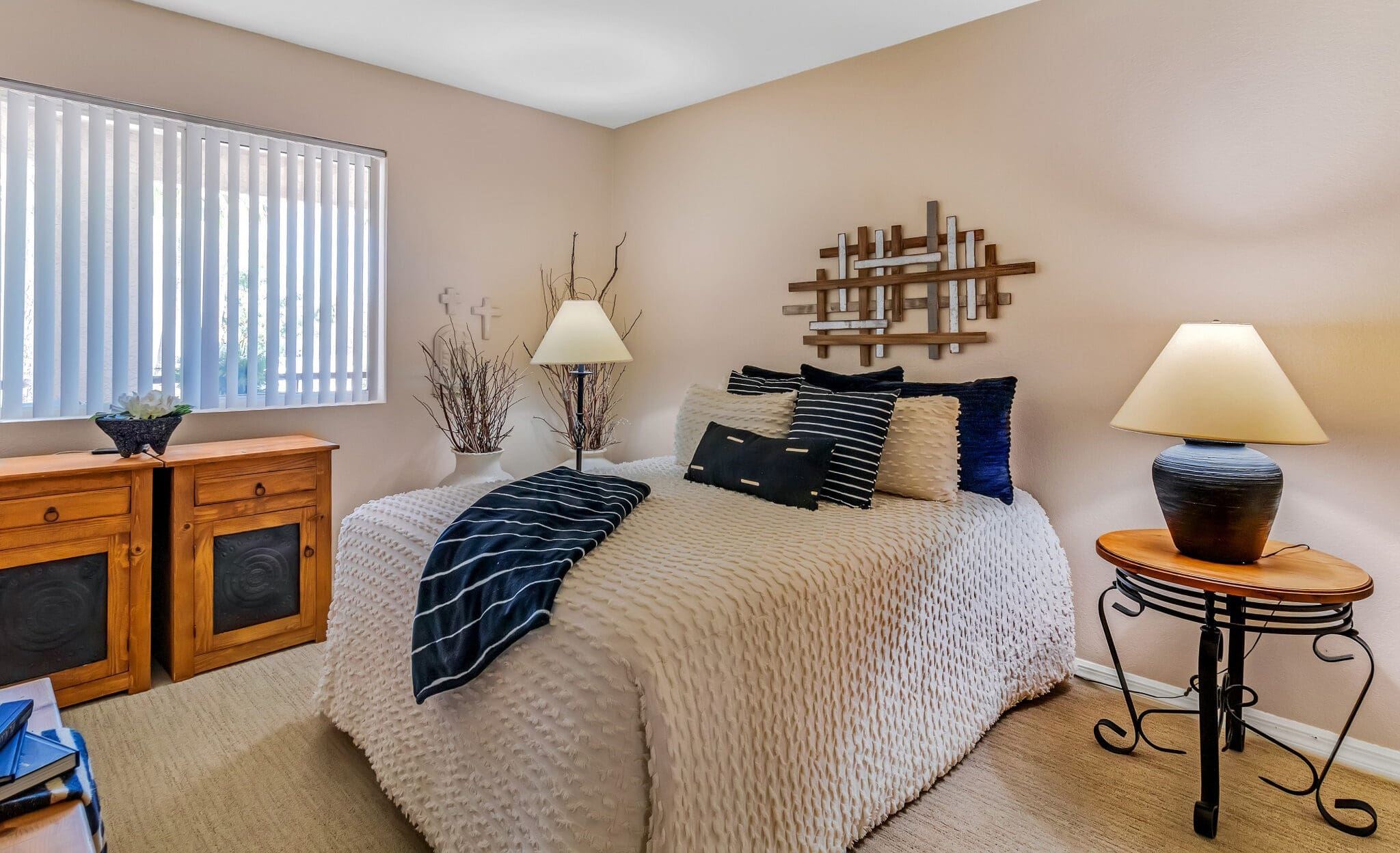 A bedroom with a bed, white sheets, and blue throw pillows, with a bedside table and lamps on each side of the bed at The Ranch Estates at Scottsdale.