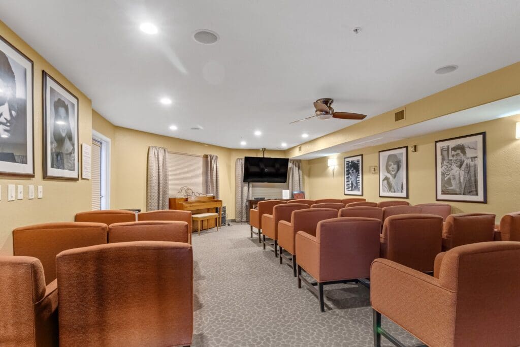 - Grace Management A sitting area with orange sofa chairs and black-and-white photograph portraits hung up all around the room at The Ranch Estates at Scottsdale.