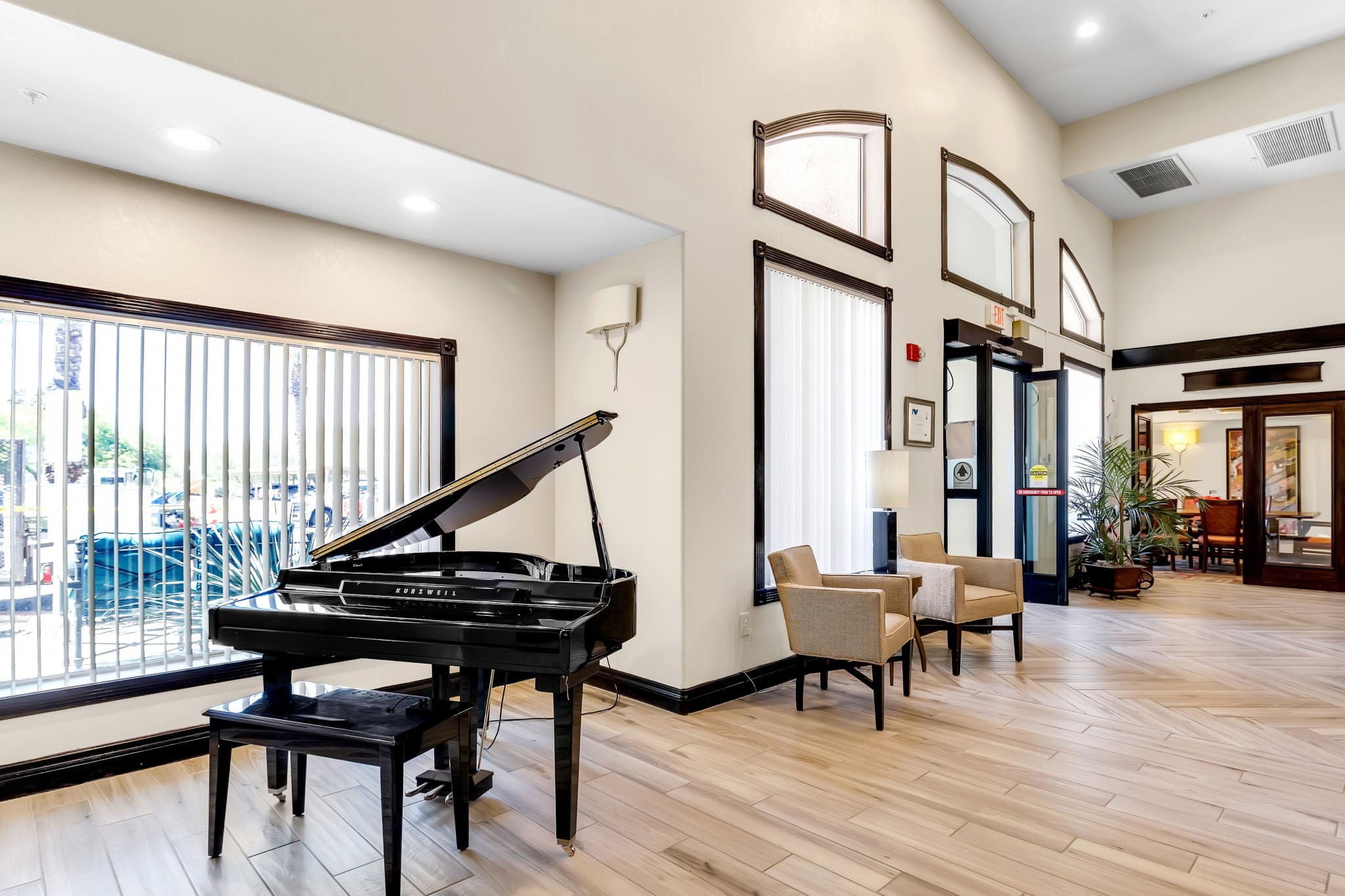 - Grace Management A lobby room with high ceilings, a black piano and two beige sofa chairs at The Ranch Estates at Scottsdale.