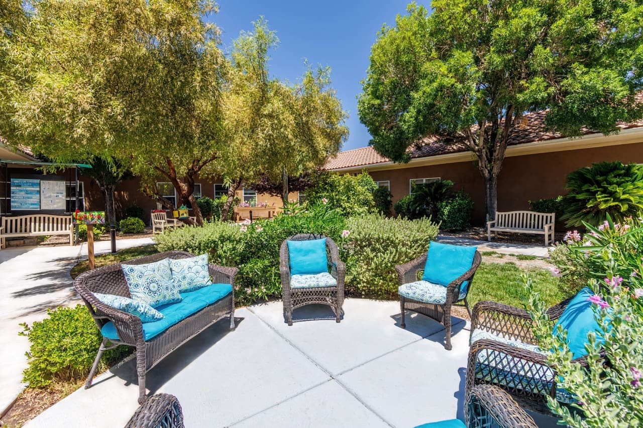 - Grace Management Courtyard area outside the building with comfortable outdoor couches and chairs arranged in a circle for visiting at Vista Pointe at Mira Loma.