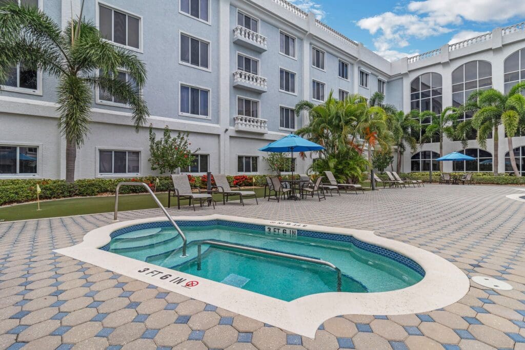 A resort-style pool, hot tub/jacuzzi, and patio at The Summit of Fort Myers, a senior living community.