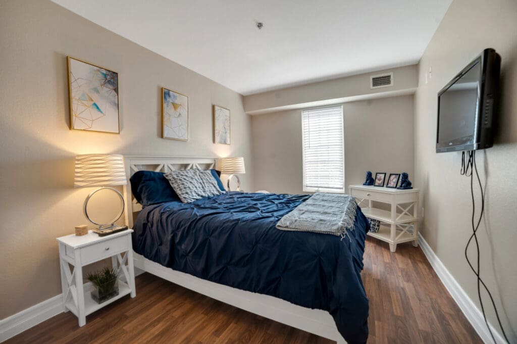 Resident bedroom with navy bedding and white furniture at Acacia Springs, a senior living community.