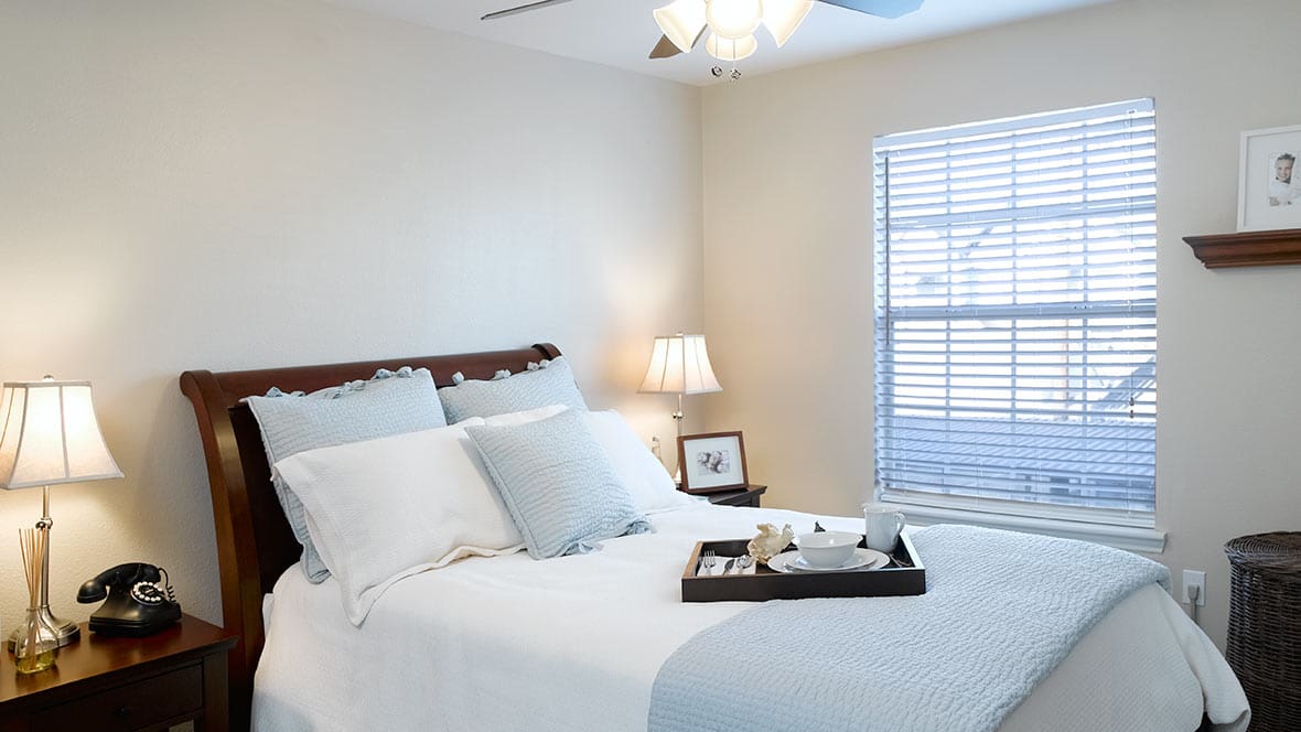 Interior shot of a Collier Park bedroom, featuring lots of natural light and comfortable furnishings.