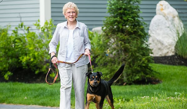 A resident walking her dog at The Highlands, a pet-friendly senior living community near Portland, ME.