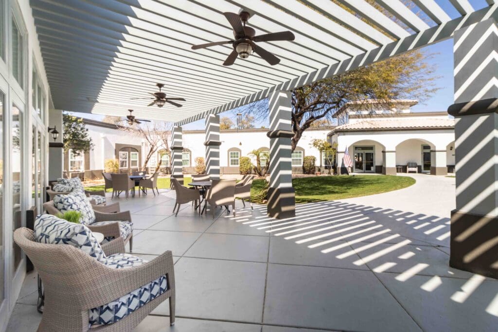 An exterior shot of Inspirations of Tempe's center courtyard with comfortable patio furniture, outdoor fans, and lots of greenery.