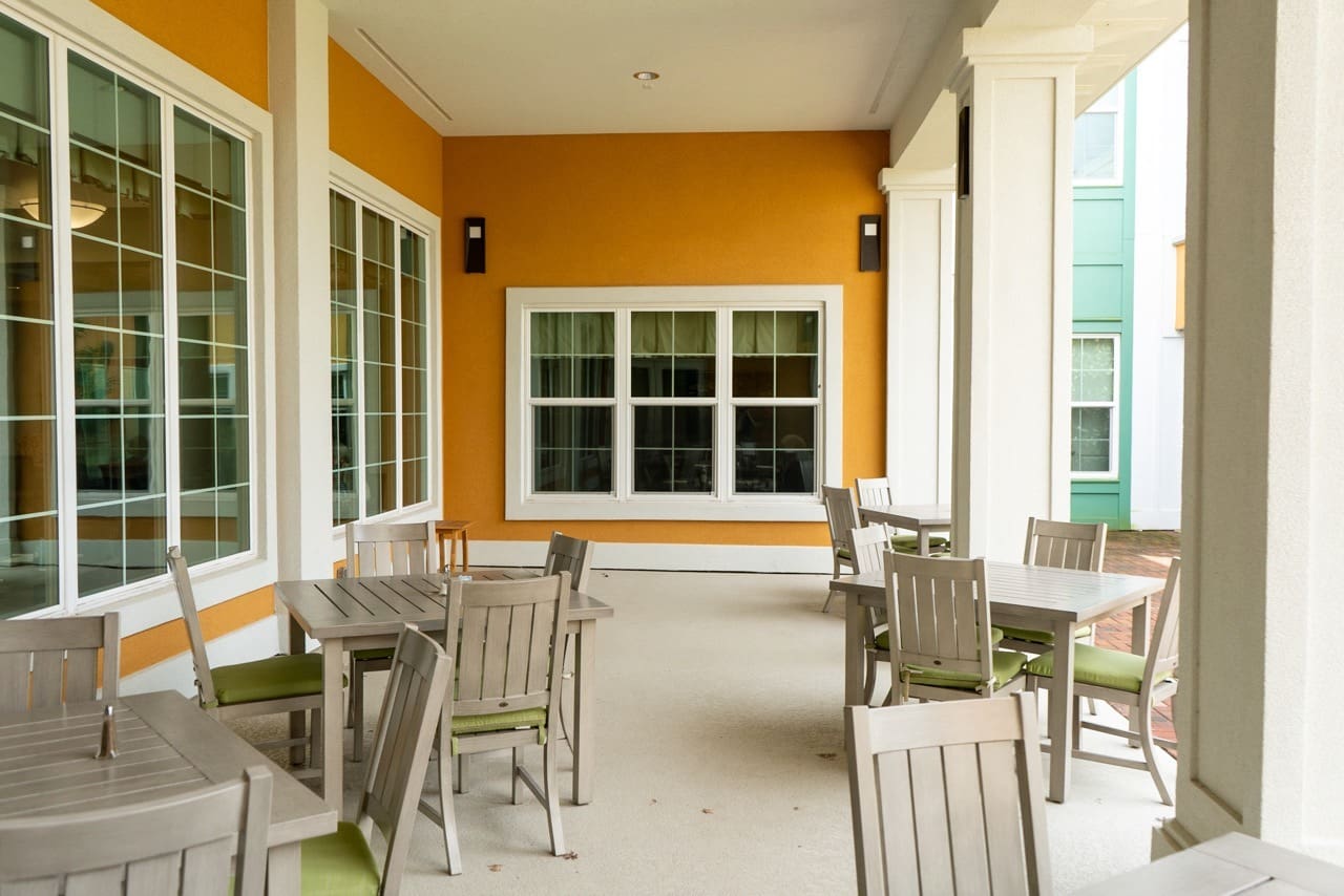 - Grace Management Exterior image of The Arbors of Gulf Breeze covered patio with comfortable furniture, facing the outdoor courtyard.