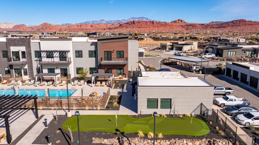 Stunning senior living community with modern architecture, inviting pool, and scenic red rock mountain backdrop.