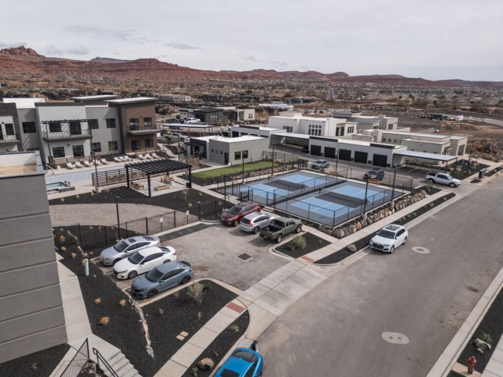 Aerial view of upscale senior living community featuring modern buildings, tennis courts, and lush outdoor spaces.
