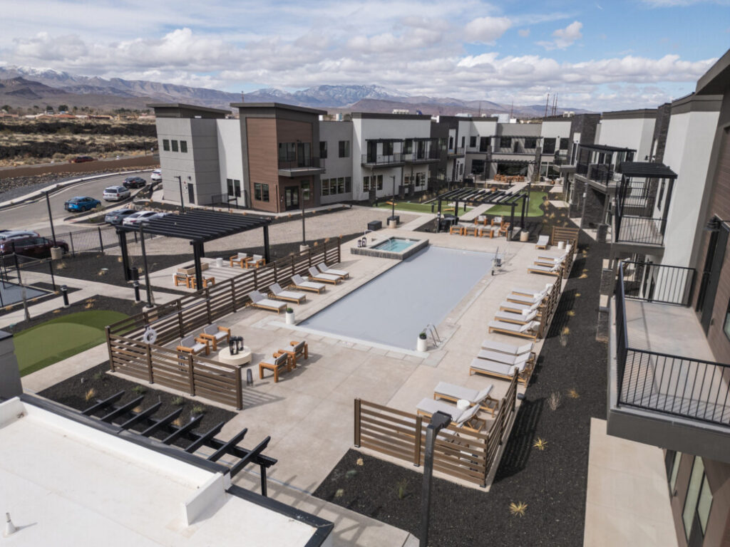 Upscale senior living community featuring a stylish pool area, lounge chairs, and scenic mountain backdrop.