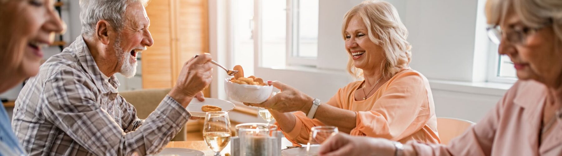 Seniors joyfully share a meal at a beautifully set table, fostering connection and vibrant community.