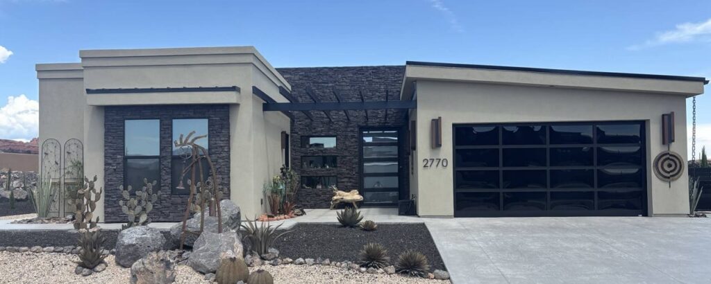 Contemporary home exterior featuring modern design, serene landscaping with cacti, and a clear blue sky.