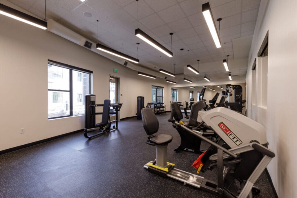 Modern fitness center featuring equipment, large windows, and a bright, welcoming atmosphere.