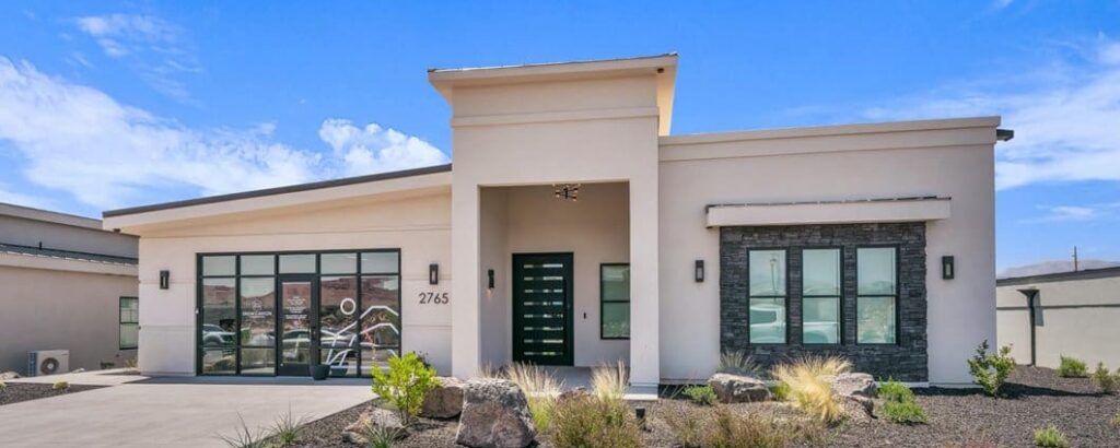 Modern senior living residence featuring elegant architecture, landscaped grounds, and inviting entrance under a clear blue sky.