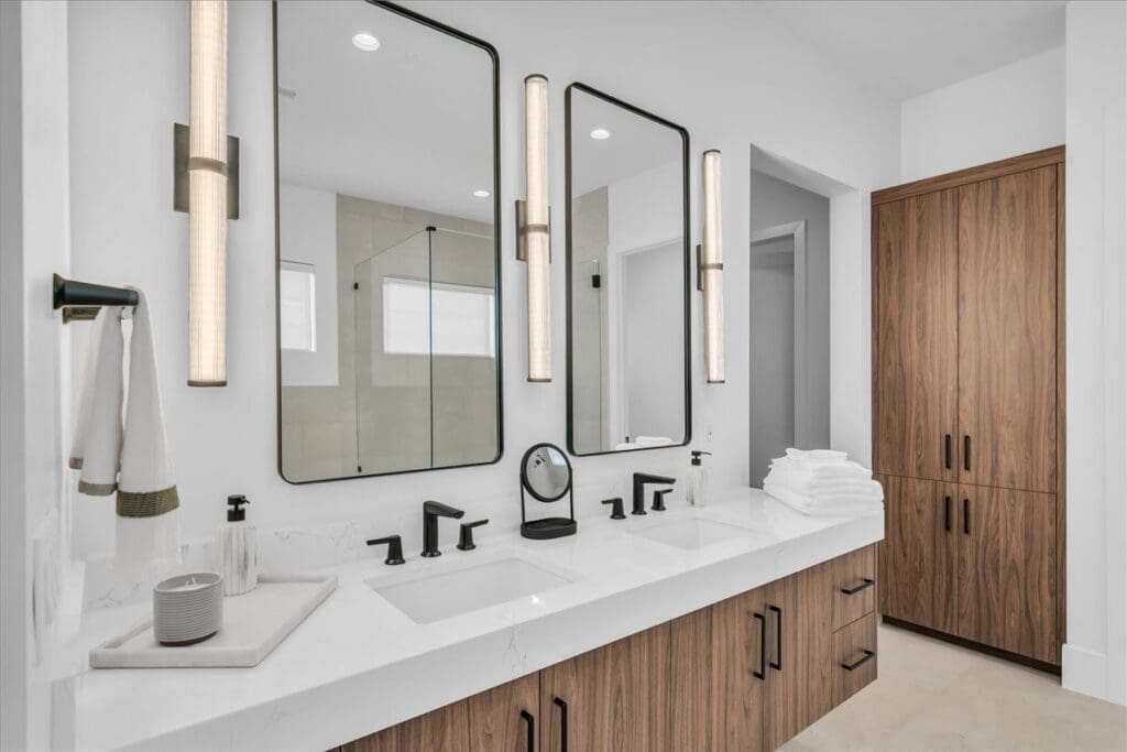 Modern bathroom featuring stylish double sinks, elegant mirrors, and upscale wooden cabinetry. Bright and inviting atmosphere.
