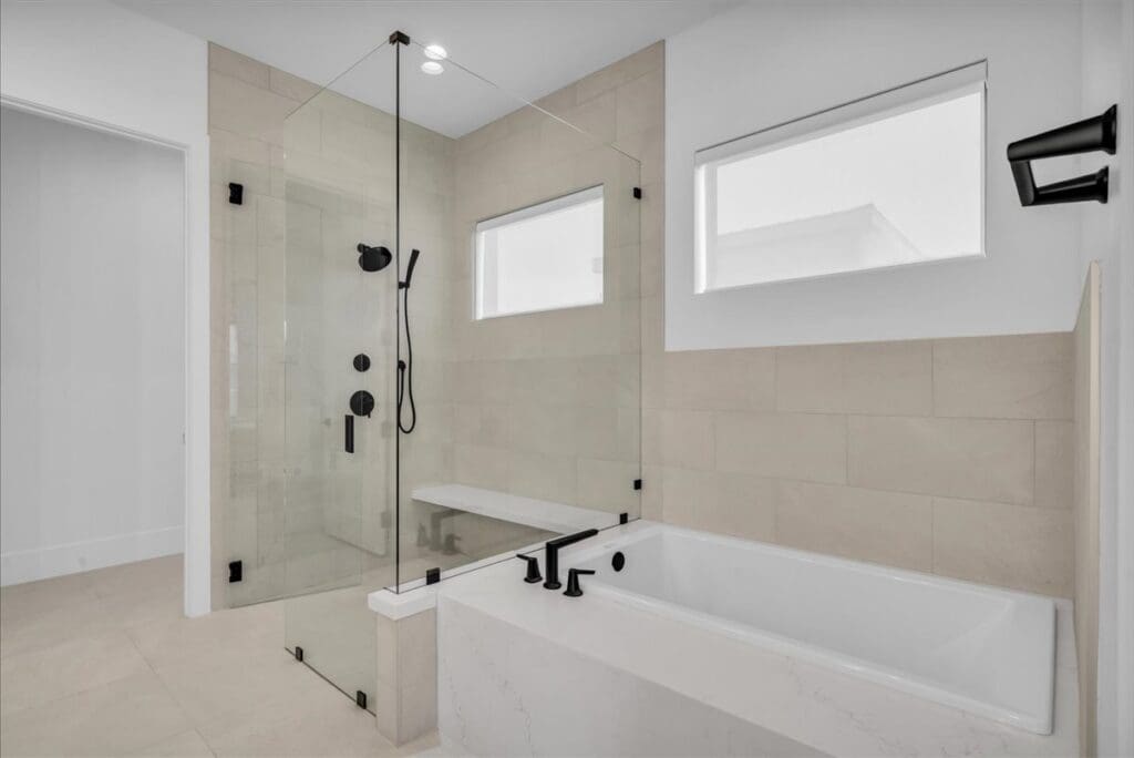 Spacious upscale bathroom featuring a glass shower, soaking tub, and modern fixtures in a light, serene setting.